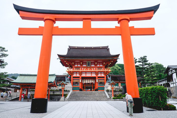 Oldman and Great Torii gate and the Romon Gate at Fushimi Inari taisha shrine, Kyoto, Japan
