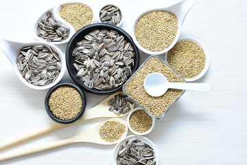 Birdseed and natural sunflower seeds, food for birds, displayed in containers on white wooden background