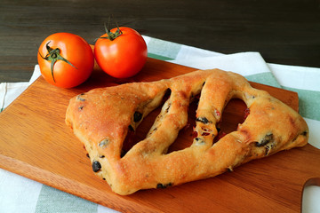 Sun Dried Tomato and Olive Fougasse French Bread with a Pair of Fresh Tomatoes on Wooden Tray
