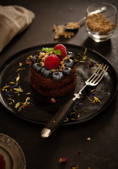 Czekoladowe babeczki z malinami i jagodami na czarnym talerzu z podświetleniem, Zdjęcie żywności w jasnych kolorach - 329643387