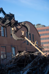 Machine lifting wooden debris at building site