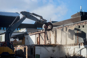 Demolition of old building , with shadow of scoop on wall