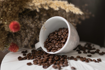 Cup with coffee beans on a background of a bouquet of flowers