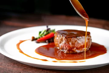 Zelfklevend Fotobehang Grilled beef tenderloin steak on a white platter is served with demiglas sauce © Andrey