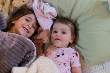 Sisters are smiling a playing before bedtime.
