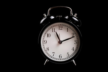 Black alarm clock isolated on a black background. Free space for an inscription.