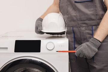 Plumber repairing washing machine, working man fixing problem