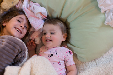 Sisters are smiling a playing before bedtime.
