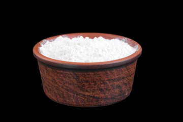 Clay bowl with flour isolated on a black background.