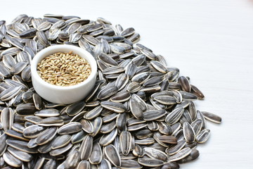 Birdseed and natural sunflower seeds, food for birds, displayed in containers on white wooden background
