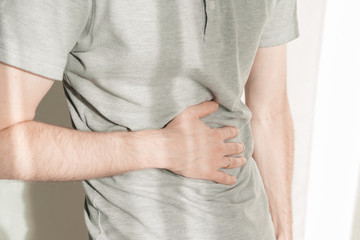 A man clings to his stomach with his hands. The man got a stomachache. Belly close up