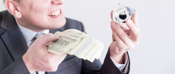 Nervous businessman in suit holds in hands drop of black oil of Brent brand and pack of dollars,...