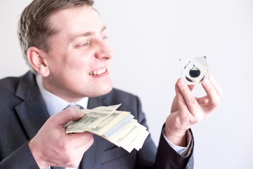 Nervous businessman in suit holds in hands drop of black oil of Brent brand and pack of dollars,...