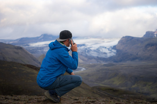 Backside of tall caucasian man calling by cellphone near over mountain of Laugavegur track in Iceland. Concept of good quality mobile coverage and technology 