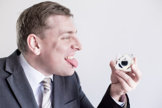 Nervous Businessman In Suit Holds In Hands Drop Of Black Oil Of Brent Brand, Screams,shows Tongue.Crystal Cube. Crisis In Financial Market, Falling And Rising Prices, Quotes, Changes In Exchange Rate