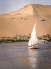 sailboat on The Nile in front of sand dunes