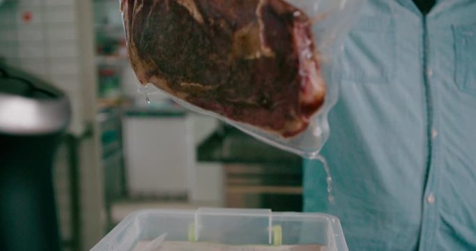 Low angle view of a man taking out the vacuum-sealed steak package form the Sous Vide Precision Cooker.