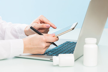Fototapeta premium Doctor's hand uses a laptop and digital tablet on a blue background. medicine concept, modern technology