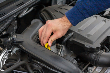 Obraz premium Closeup of mechanic hands checking motor under the hood in the broken car. Repairing of the vehicle concept. Automobile service