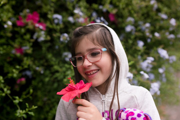 A girl is smelling flowers while out on a nature walk.
