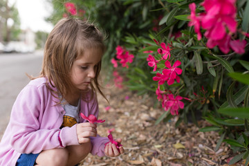 A girl is smelling flowers and enjoying some outside nature time while in quarantine.