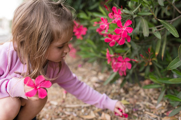 A girl is smelling flowers and enjoying some outside nature time while in quarantine.