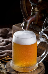 Light frothing beer in a glass, on an old background.