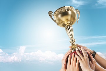 Hands holding a champion golden trophy on sky background