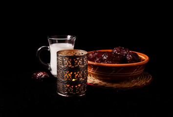 Ramadan lamp and dates with cup of milk, still life on a black background.