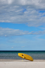 Yellow surfboard on a sandy beach
