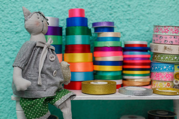 set of many colors satin ribbons in rolls in background. Rolls of bright colored satin ribbons close up. Shelf with Satin ribbons in the store a large selection. materials for handmade products