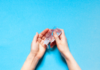 A person is using antibacterial transparent  hand sanitizer gel in a plastic bottle. Coronavirus (Covid-19) preventive measures top view concept 