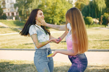 Fototapeta premium Friends with a holi paints. People in a summer park. Girls have fun.