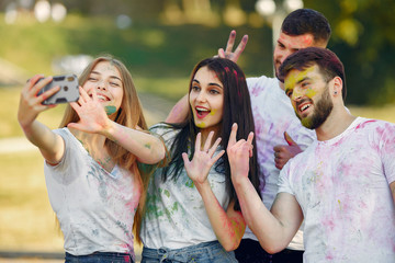Friends with a holi paints. People in a summer park. Students have fun.