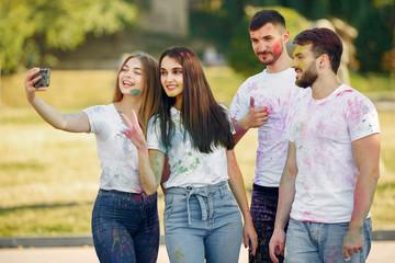 Friends with a holi paints. People in a summer park. Students have fun.