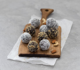 Energy candy balls made of dried prunes, dates, dried apricots and almonds, cashews, walnuts, with walnut and coconut topping on a wooden Board on a light background