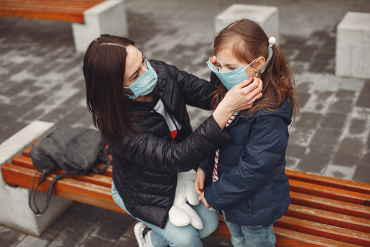 Woman in a disposable mask is teaching her child to wear a respirator.