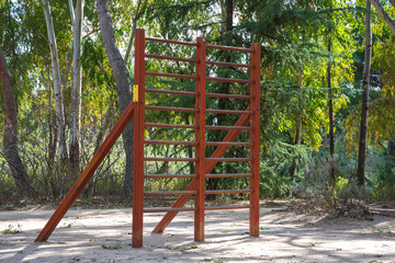 Fototapeta premium View of wooden apparatus for training in a sports area of a park with trees, in Madrid, Spain. Horizontal