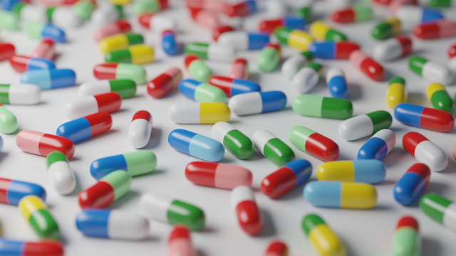 Multicolored pills on white background. Medical treatment, pharmaceutical industry concept. Digital 3D render.