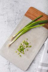 Whole and Chopped Green Onions on Cement Cutting Board on Cement Countertop