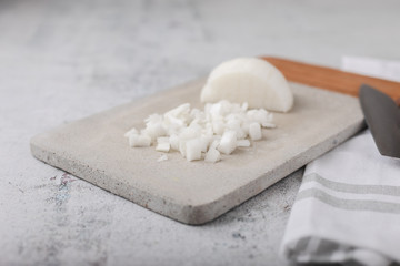 Chopped White Onions on Cement Cutting Board on Cement Countertop