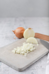 Whole and Chopped Sweet Onions on Cement Cutting Board on Cement Countertop