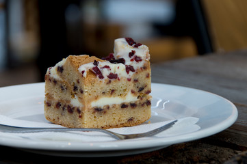 piece of cheesecake with cranberries on white plate