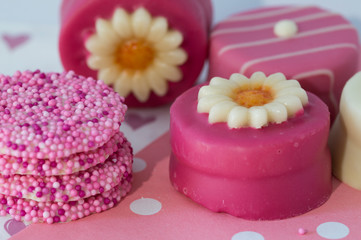 Fototapeta na wymiar pink petit fours with sprinkles and marzipan flower.