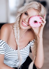 Portrait of beautiful young blonde woman with makeup with pink donut