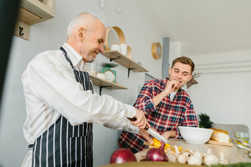 Young man and his father cooking in kitchen