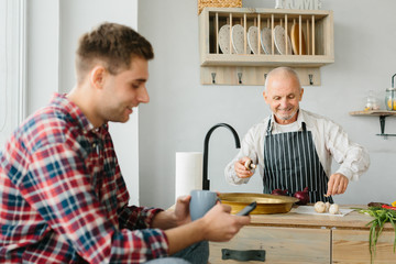 Young man and his father cooking in kitchen