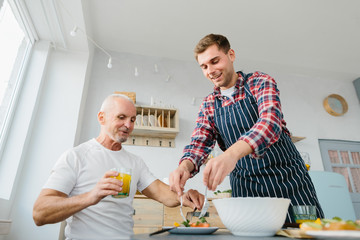 Young man and his father cooking in kitchen