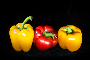 Red Pepper between two Yellow Ones on Black