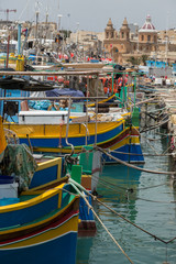 Colourful striped, painted fishing boats tied-up at Marsaxlokk, Malta